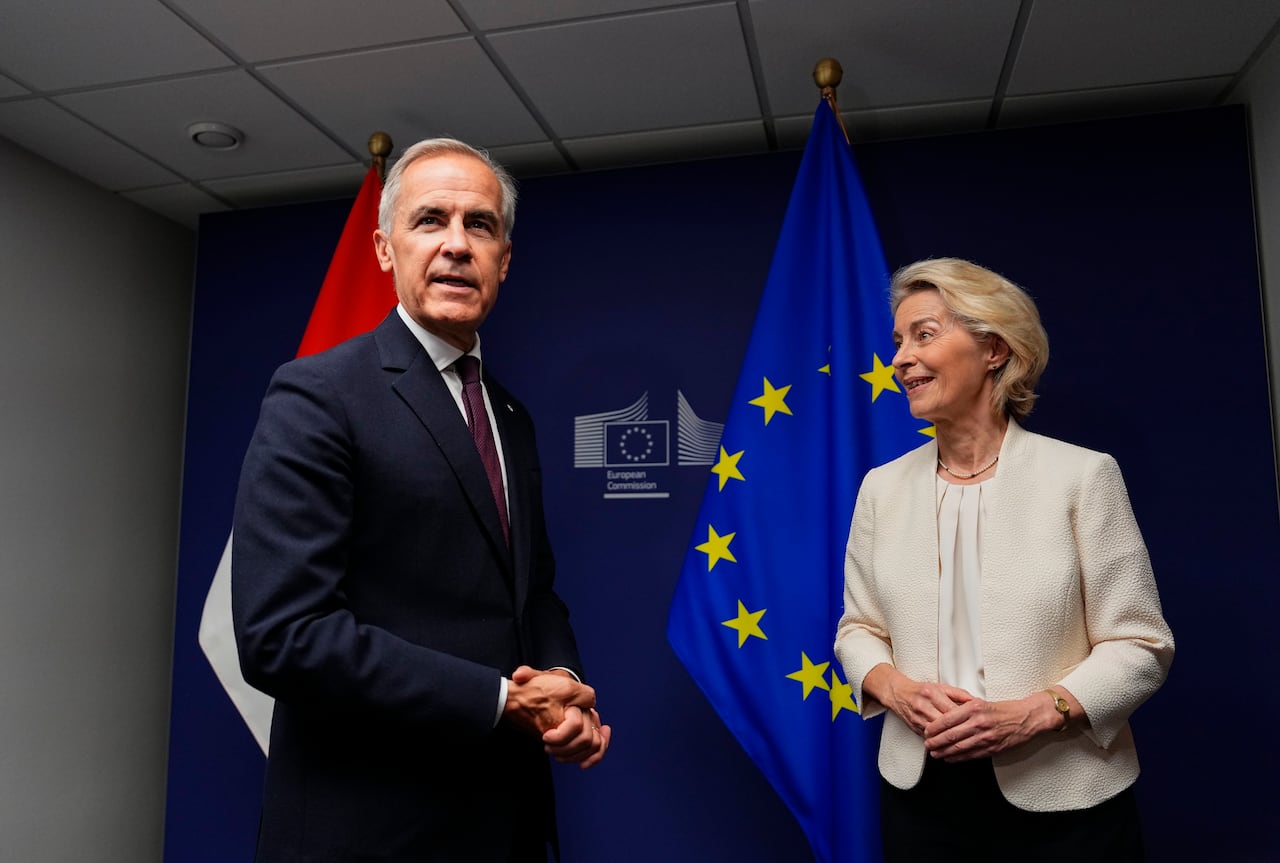 A man with grey hear, wearing a black suit, stands picture left beside a woman with short blonde hair wearing a cream jacket.