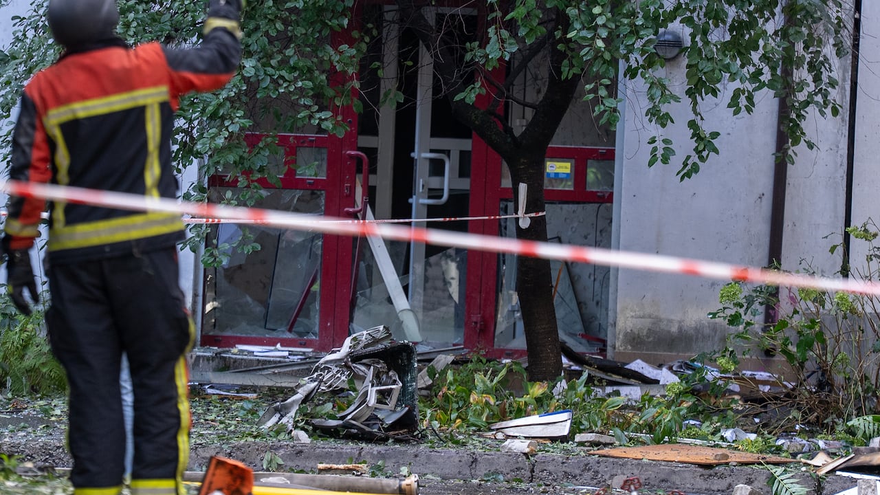 A firefighter stands by debris from what appears to be a jet-powered drone engine.