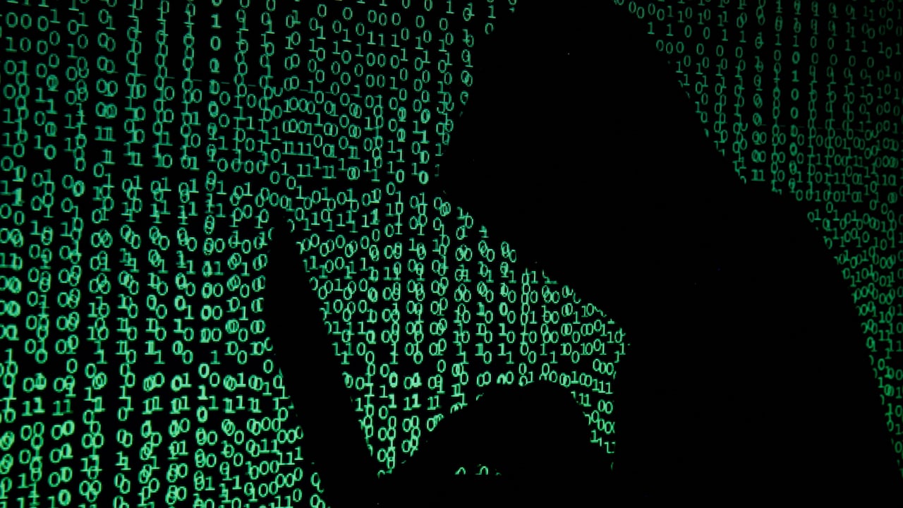 Computer code shown behind a silhouetted person wearing a hoodie
