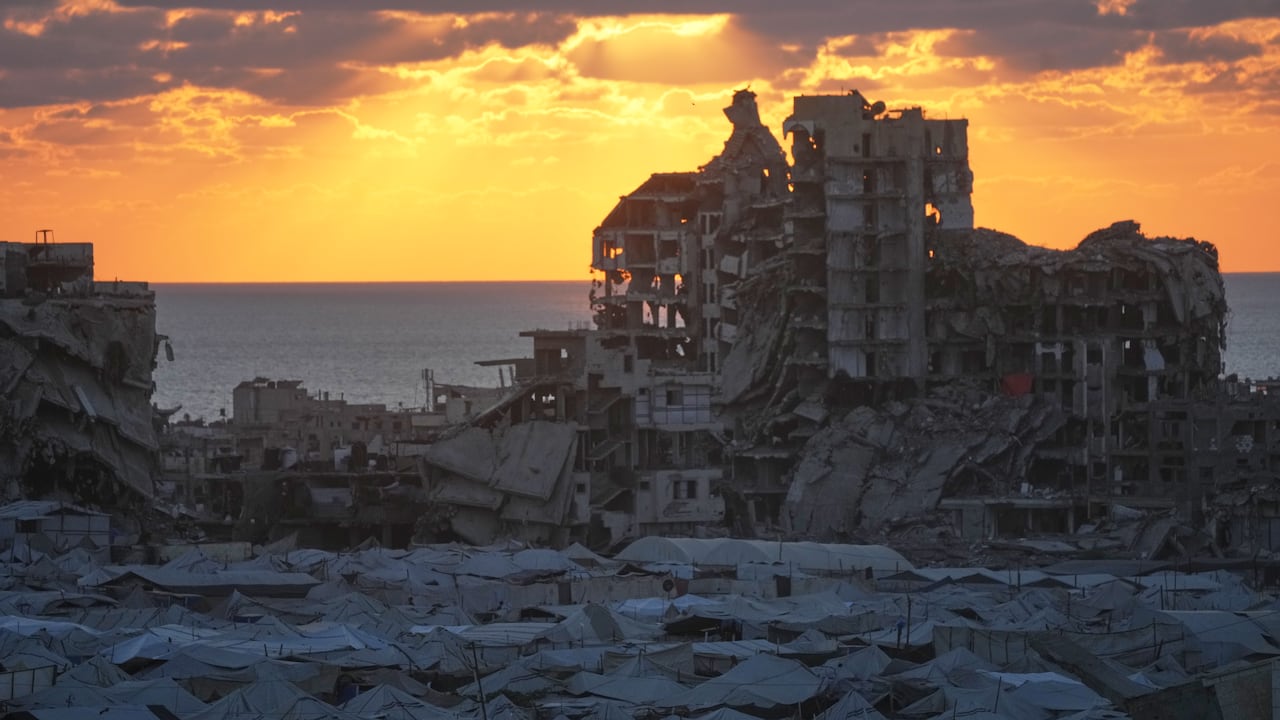 Rows of tents with a damaged building in the background.