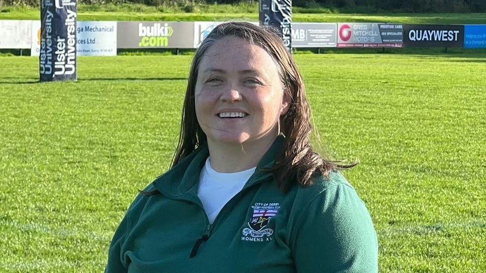 Girl with dark hair, wearing a green jacket. 