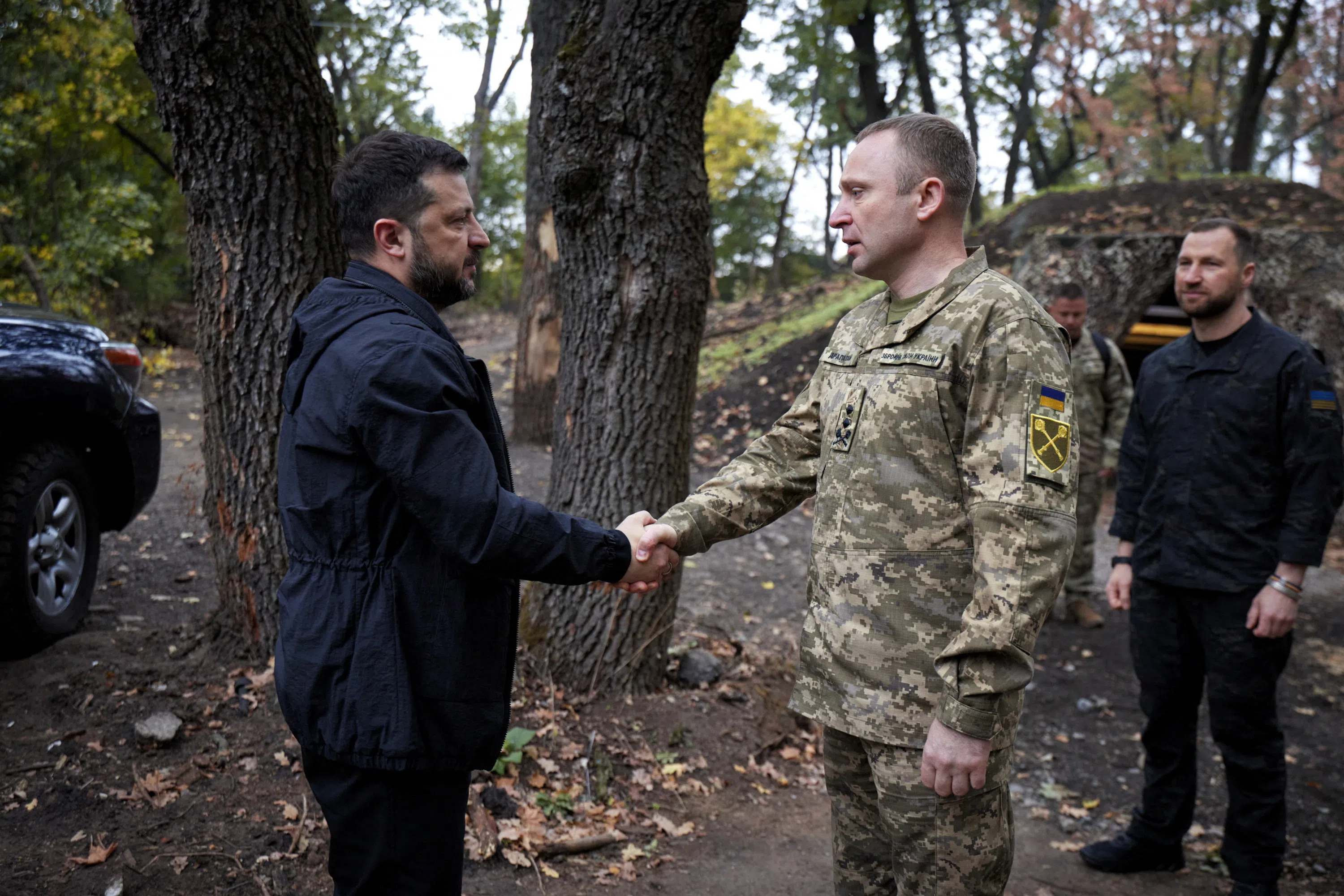 Ukraine's President Volodymyr Zelenskiy and Commander-in-Chief of the Ukrainian Armed Forces Major General Mykhailo Drapatyi shake hands as they visit service members of the 66th Separate Mechanized Brigade named after Prince Mstyslav the Brave with Ukrainian Defence Minister Yevhenii Khmara, amid Russia's attack on Ukraine, near the front line in Donetsk region, Ukraine, September 30, 2026. Ukrainian Presidential Press Service/Handout via REUTERS