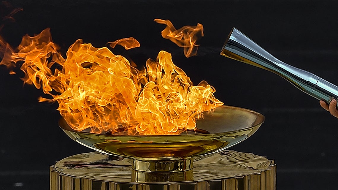 Actress Mary Mina lights the Olympic torch during the Olympic flame handover ceremony for the Milano-Cortina Winter Games at Panathenaic Stadium on December 4, 2025 in Athens, Greece.