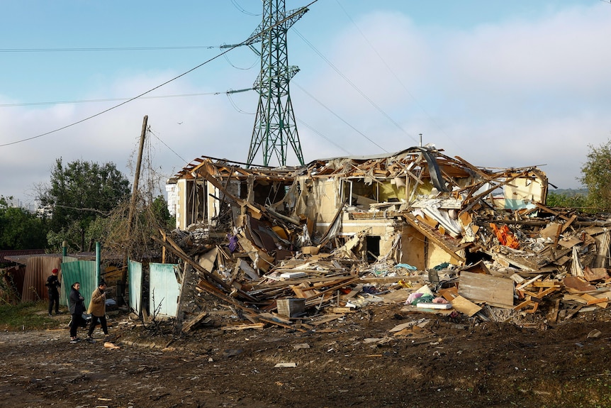 A destroyed home with power lines in the background.