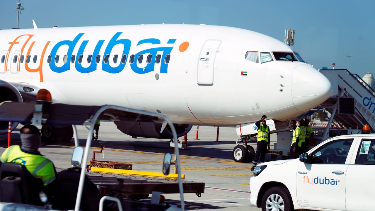 A FlyDubai passenger jet sits on a tarmac as workers prepare a flight.