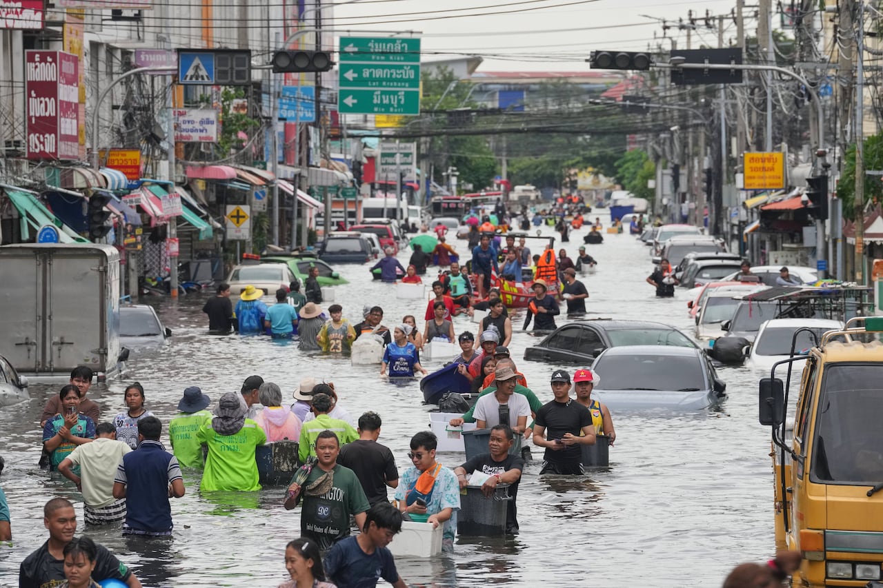 A wide-city street stretches into the distance, with dozens of people wading through hip-deep water.