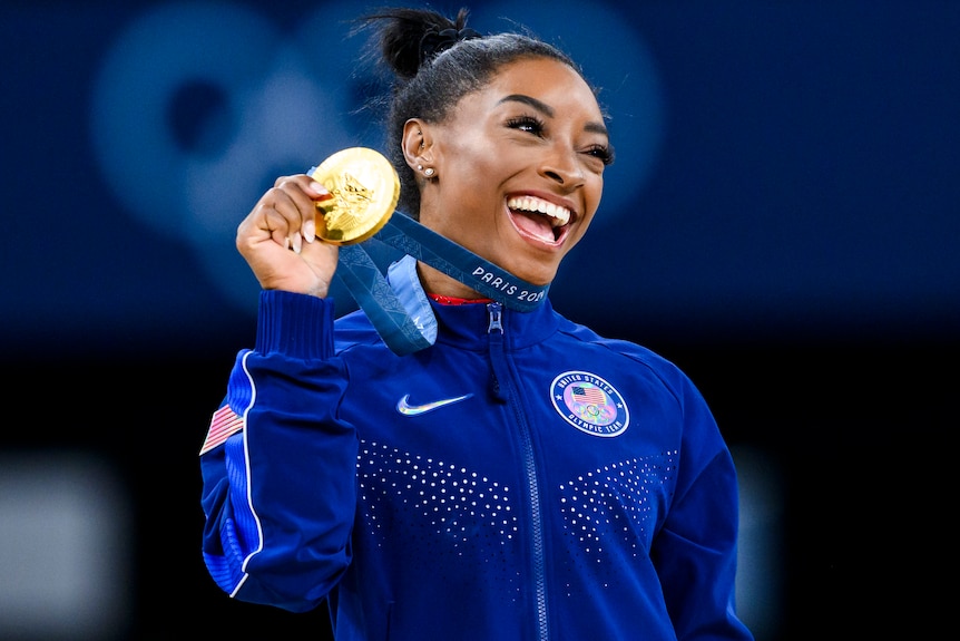 Simone Biles holds an Olympic gold medal at the 2024 Paris Games.