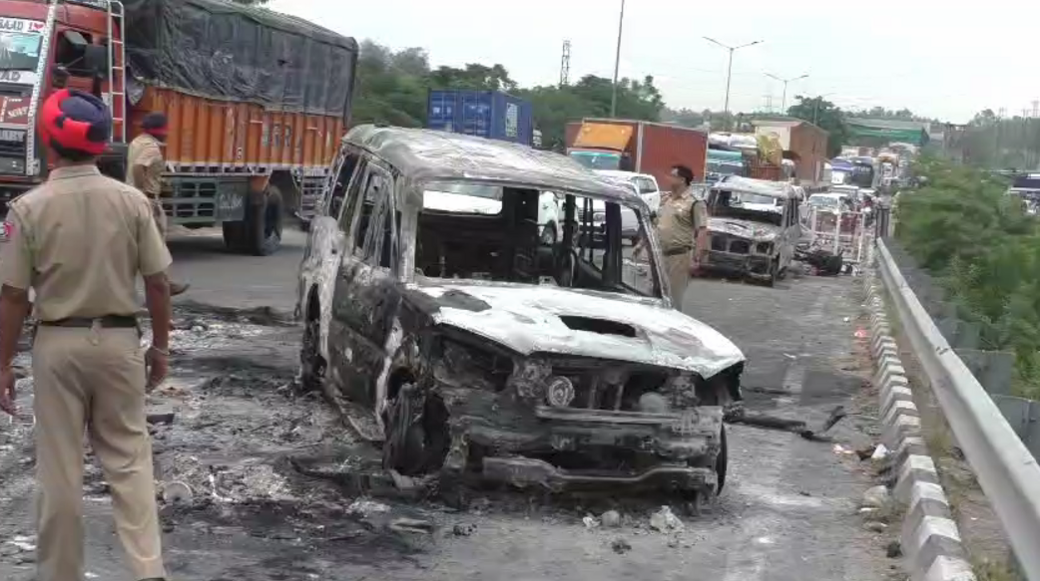 A torched car with policemen standing around it 