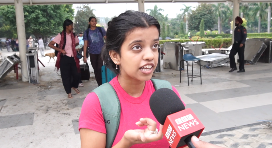 A students wearing a pink t-shirt speaks into the mic 