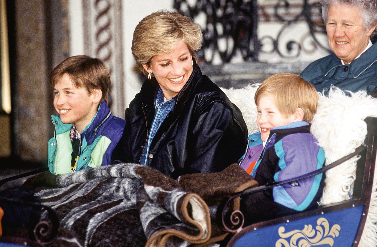 A woman and two boys on a sled, smiling