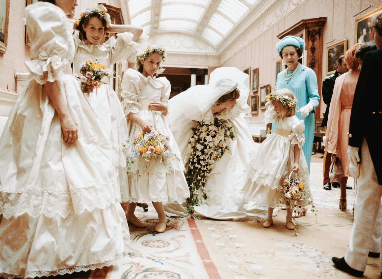 A woman in a bridal gown surrounded by bridesmaids