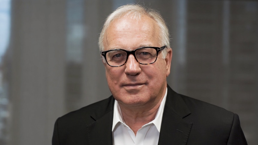Alan Kohler, wearing a dark jacket, white shirt and glasses, looks at the camera.
