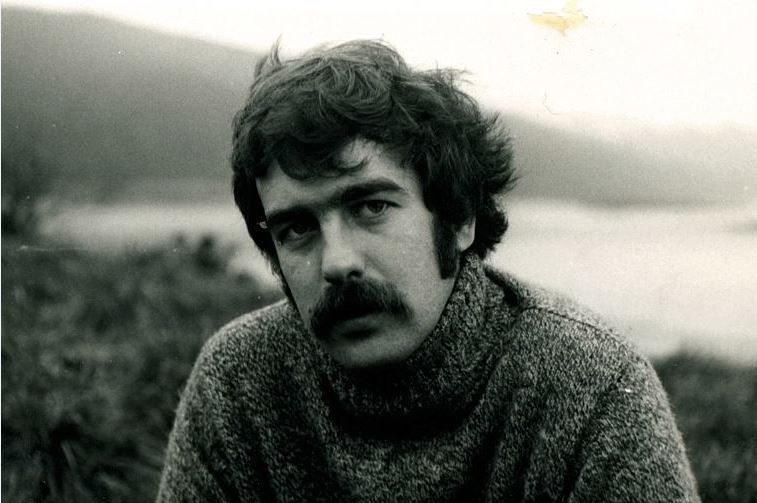 A black and white photo of a young Alan Kohler, with thick hair and a moustache, outside.