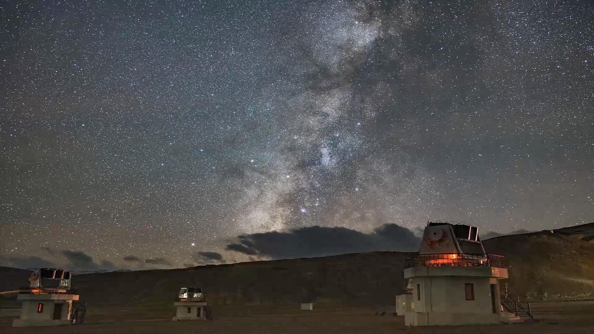 Telescopes standing in between hills with the milky way visible in Hanle, Ladakh