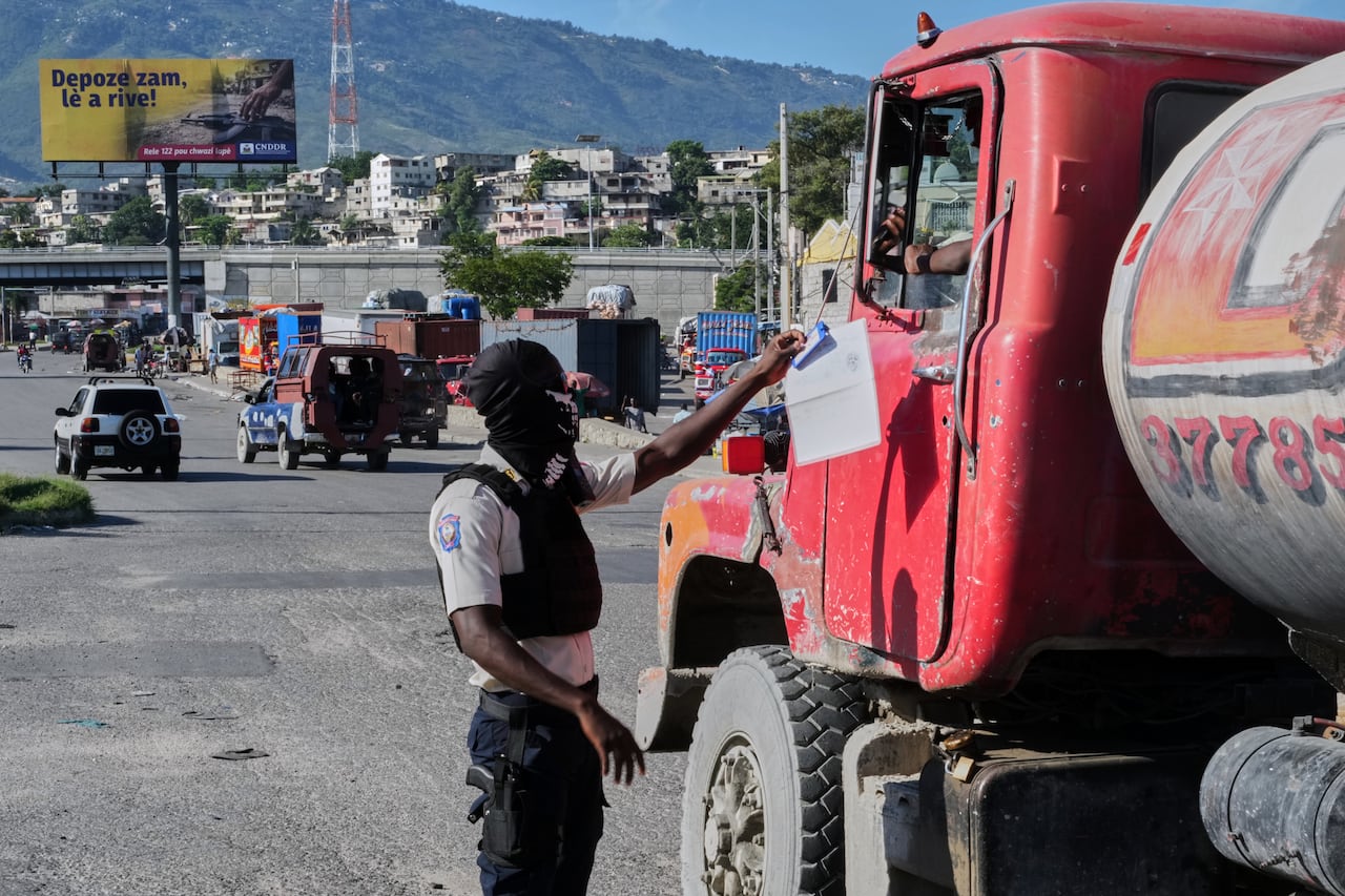 A masked police officer interacts with a truck drive in Port-au-Prince, Haiti.