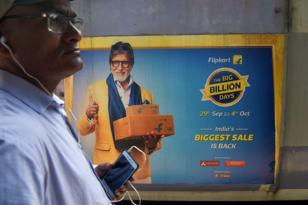 In this photograph taken on September 26, 2019, a commuter looks on as a train with advertisements of the upcoming festive sale of an online e-commerce portal featuring Bollywood actor Amitabh Bachchan passes by in Mumbai. 