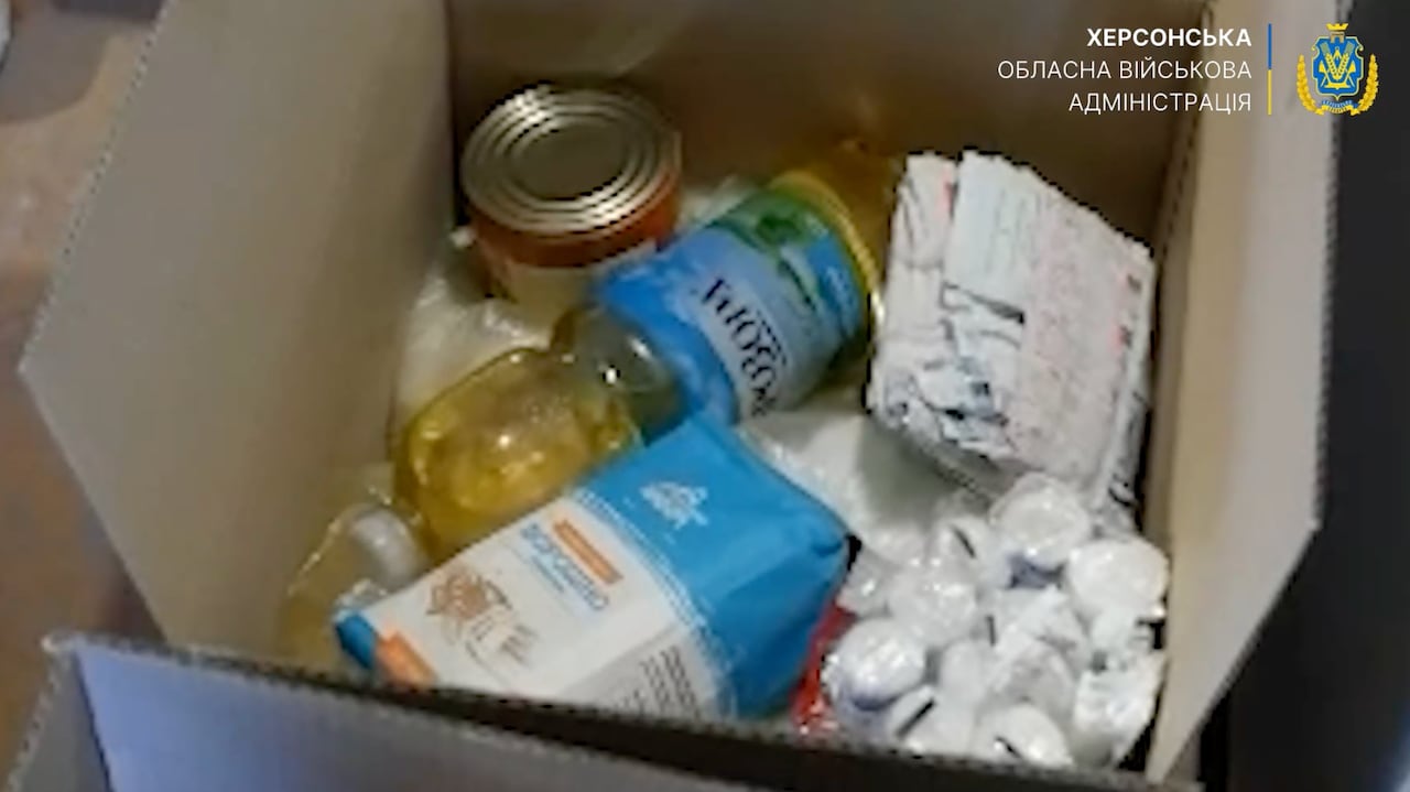 A cardboard box contains cooking oil, canned food and other supplies.