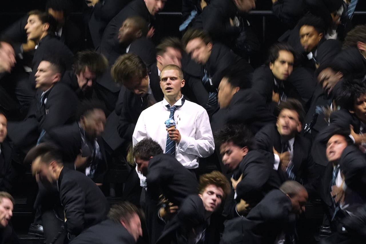 A man in white among a sea of dancers dressed in black.