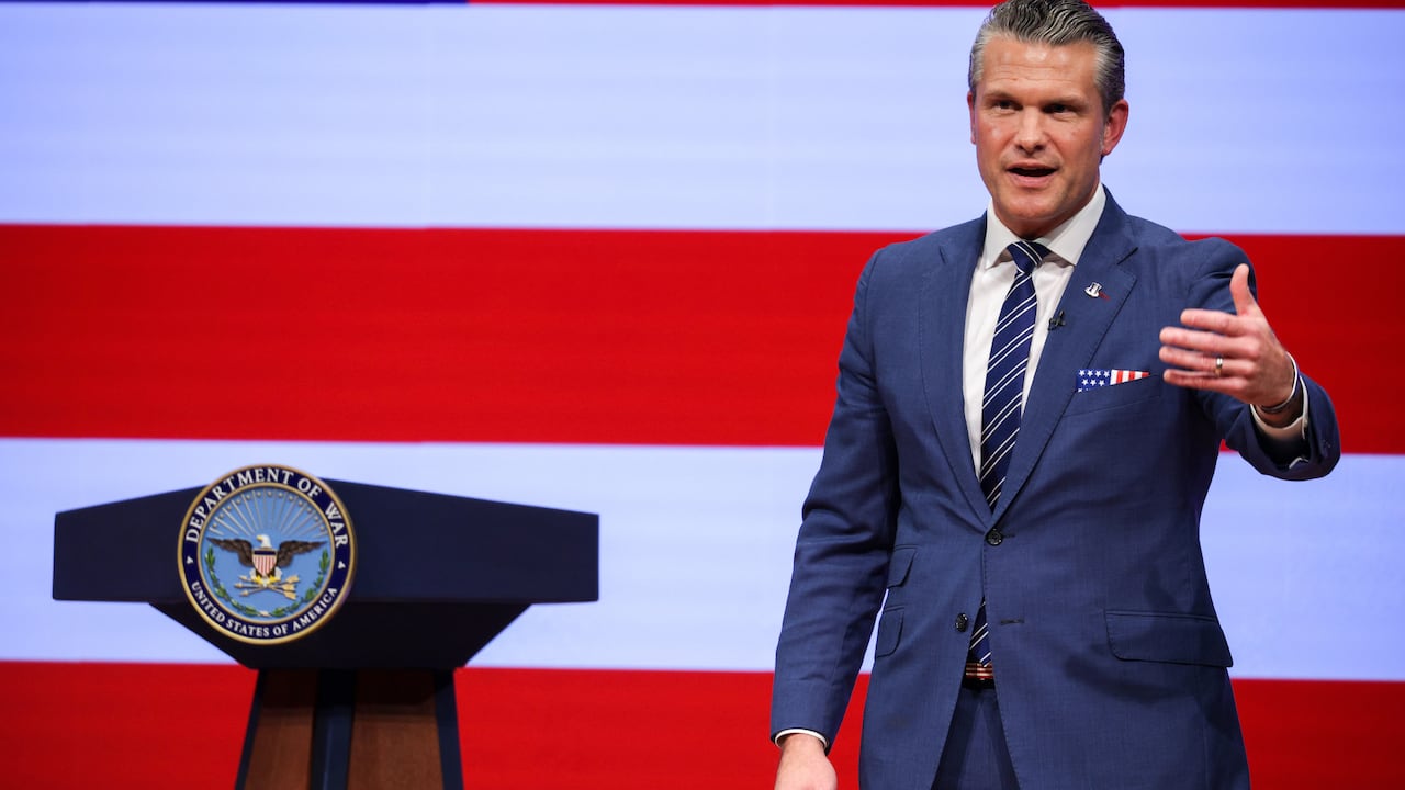 Man speaking beside a podium with red and white stripes behind him