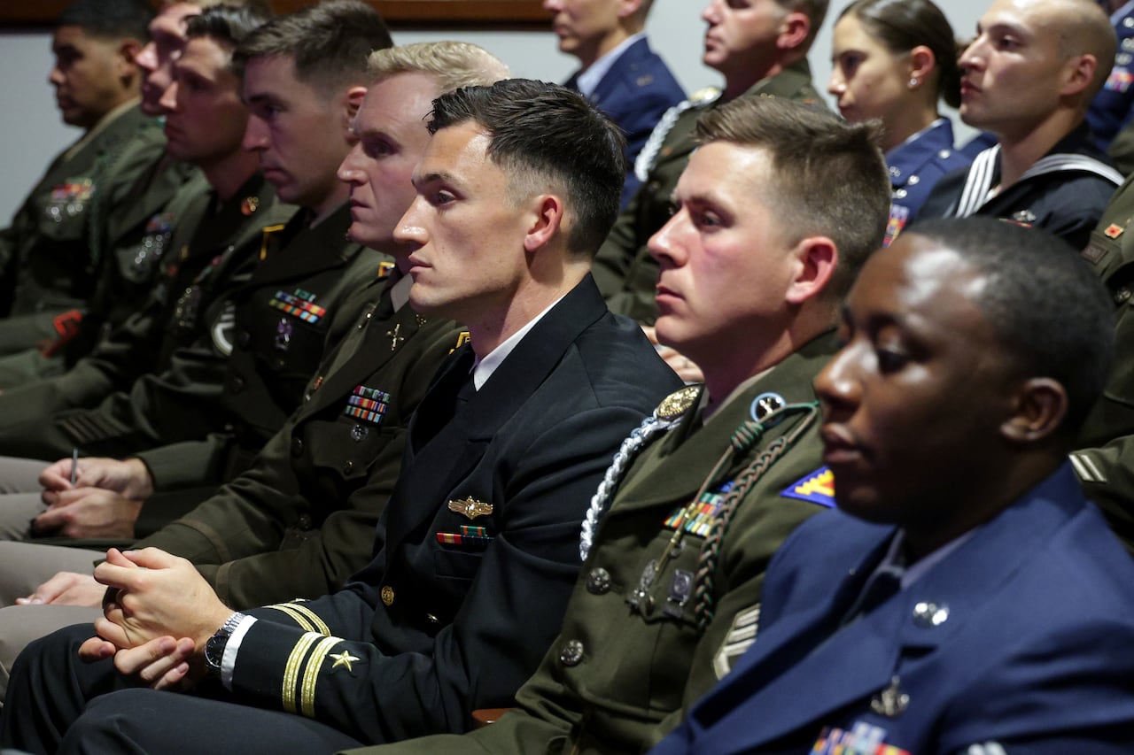 People in uniforms sit and listen in audience