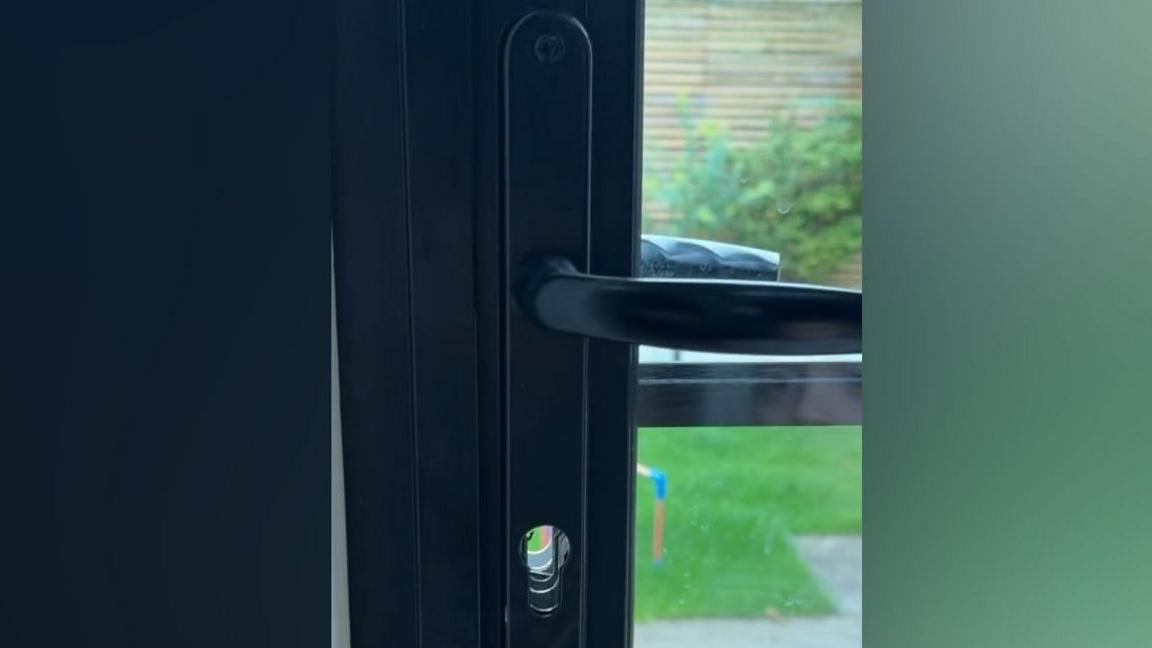 The lock on a set of bi-fold doors has been punched out, leaving a circular hole. 