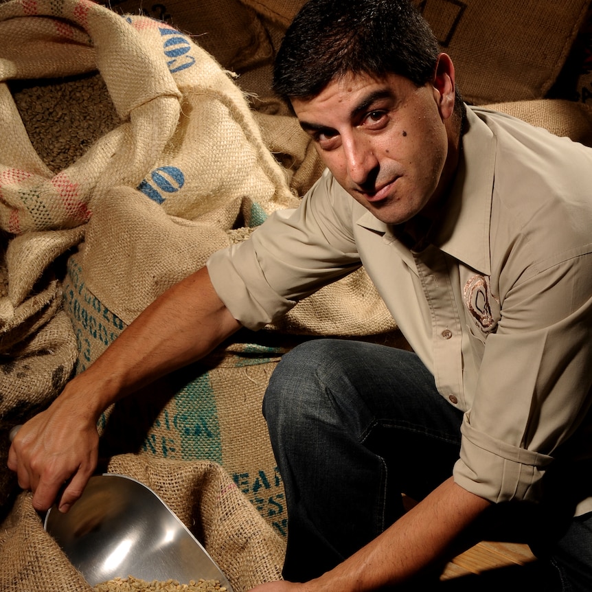Man with short dark hair, looking inside bag of coffee beans