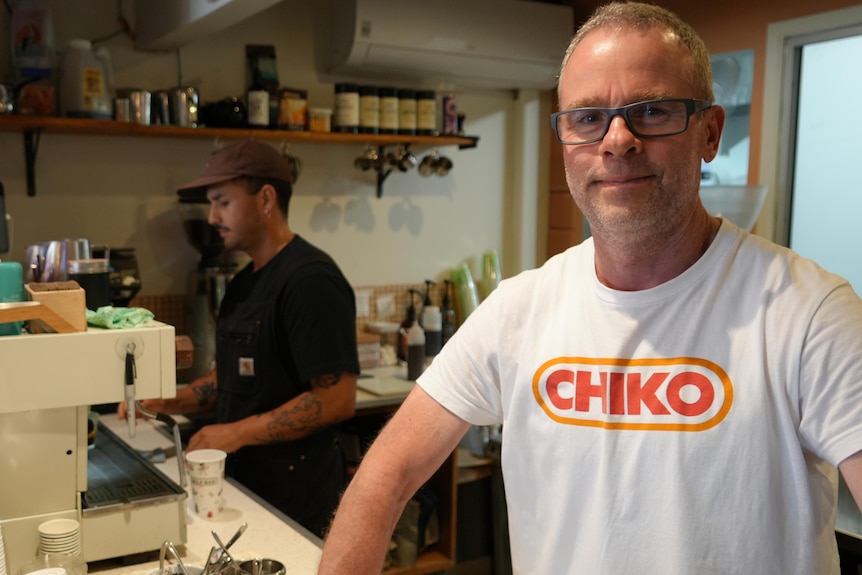 Man in tshirt at counter of cafe with barista behind him