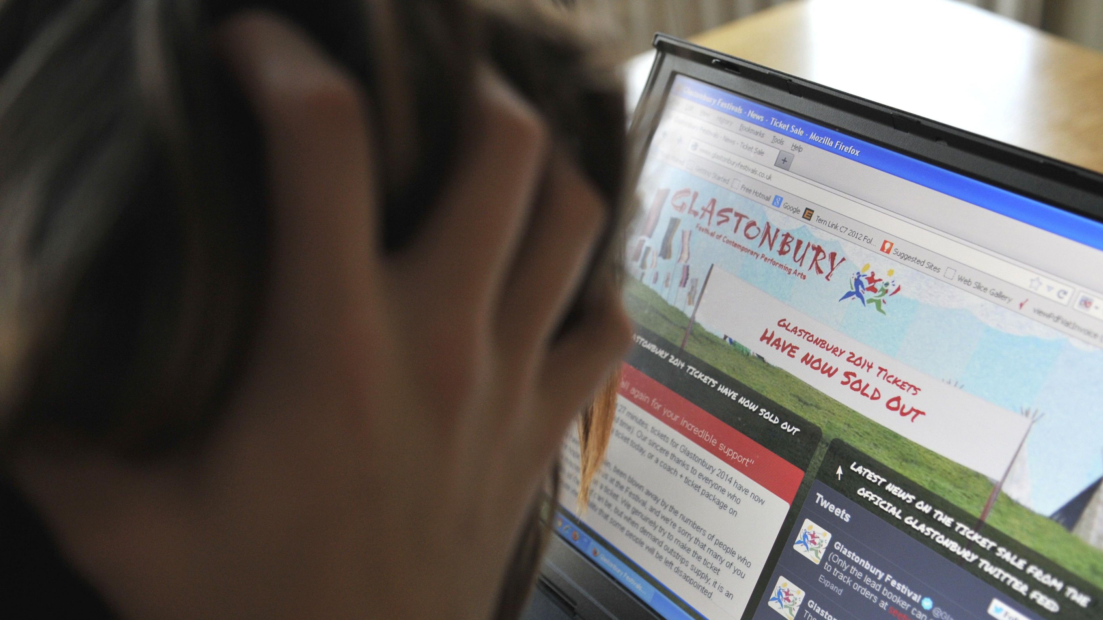 A person looking at a screen that says Glastonbury Festival tickets have sold out